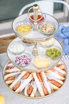 a three tiered tray with hot dogs and condiments on the bottom layer