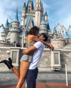 a man and woman hugging in front of a castle