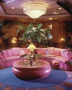 a living room filled with pink couches and lots of plants