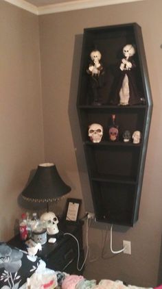 a black shelf with skulls on it next to a lamp and a bed in a room