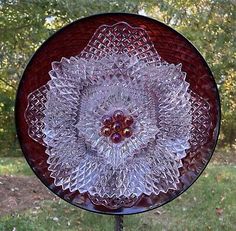 a glass plate sitting on top of a metal stand in front of a grass covered field