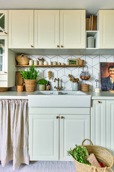 a kitchen with white cabinets and lots of potted plants