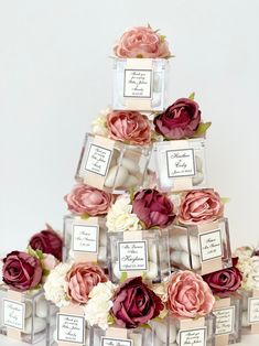 a wedding cake made out of small square boxes with flowers on the top and name tags attached to them