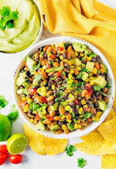 a white bowl filled with black bean salsa surrounded by tortilla chips and avocado