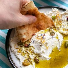 someone is dipping some kind of pita bread with olives and other toppings