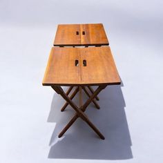 two wooden folding tables sitting next to each other on top of a white flooring