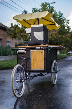 a bike with an umbrella on the back is parked in front of a food cart