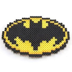 a batman logo made out of legos on a white surface with yellow and black dots