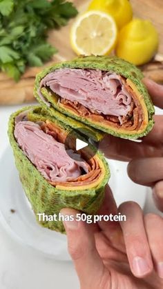 a person is holding a sandwich with meat and vegetables in the background that reads, that has 50g protein