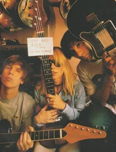 three people sitting next to each other with guitars on their heads and one person holding a guitar