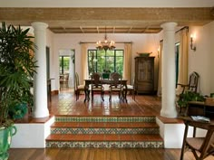 a living room filled with lots of furniture and plants on top of wooden flooring