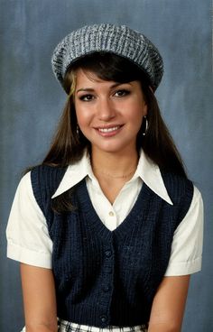 a young woman wearing a blue vest and hat