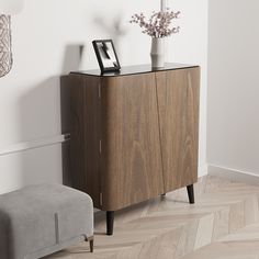 a wooden cabinet with two vases on top of it next to a gray ottoman