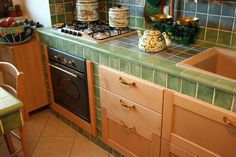 a kitchen with green tile and wooden cabinets