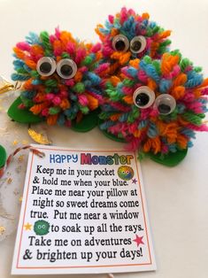 two colorful stuffed animals sitting on top of a table next to a sign that says happy monster