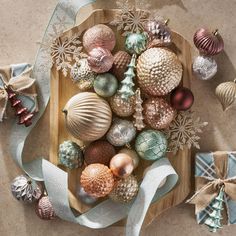 an overhead view of christmas ornaments on a wooden platter with ribbons and snowflakes