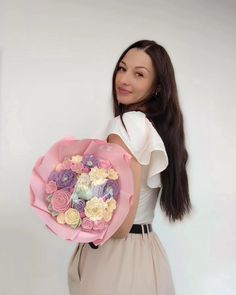 a woman holding a bouquet of flowers in her right hand and looking at the camera