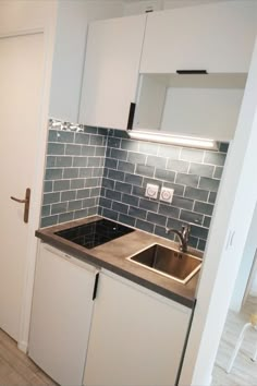 a kitchen with white cabinets and black counter tops next to a door that leads to a hallway