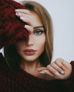 a woman with long hair and blue eyes holding her hands up to her face while looking at the camera