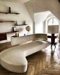 a couch sitting on top of a wooden floor in a living room next to a lamp