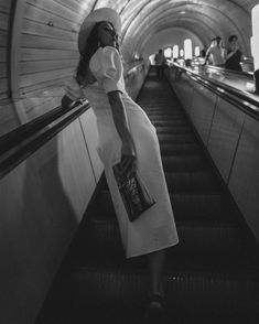 a woman is standing on an escalator in a subway station