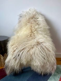 the back end of a sheepskin rug on top of a wooden floor next to a wall