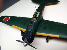 a green and yellow model airplane on a white table with red circles around the wings