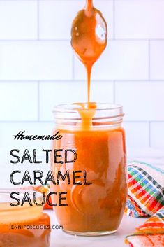 homemade salted caramel sauce in a glass jar with a spoon pouring it into the jar