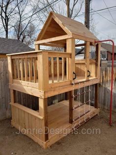 a wooden play house built into the side of a fenced in area with stairs