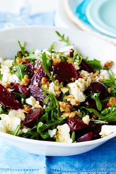 a salad with beets, feta cheese and walnuts in a white bowl