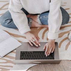 a woman is sitting on the floor with her laptop