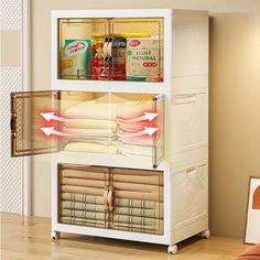 an open refrigerator sitting on top of a wooden floor