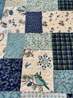 a blue and white patchwork quilt with birds on it's side, in the middle