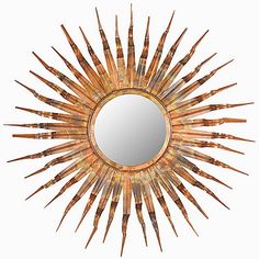 a mirror that is sitting on top of a white wall and has spikes in it