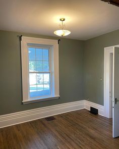 an empty room with hard wood floors and white trim on the walls, painted green