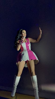 a woman in a pink and white outfit on stage with her arms out to the side