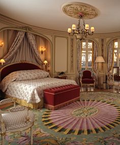 a fancy bedroom with an ornate bed and red upholstered chair in the corner