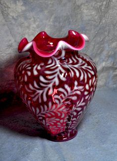 a red and white vase sitting on top of a table