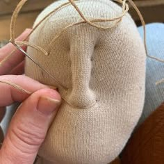 someone is stitching the ends of a doll's head