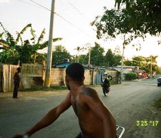 a shirtless man riding on the back of a motorcycle down a street