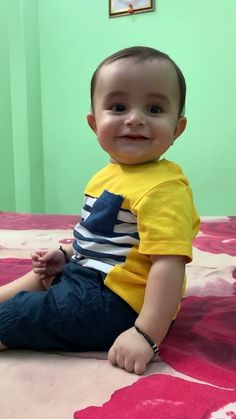 a little boy sitting on top of a bed in a room with pink and green walls