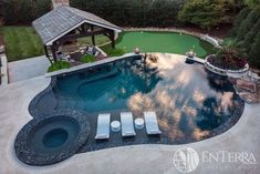 an aerial view of a swimming pool with lounge chairs and gazebo in the background