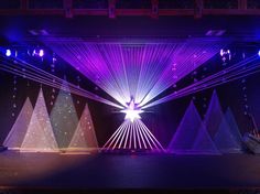 the stage is lit up with purple and blue lights, as well as white christmas trees