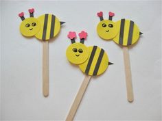 three bees on sticks with pink flowers in the middle and one is made out of pops