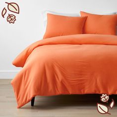 an orange comforter and pillows on a bed