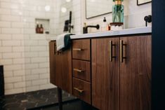 a bathroom with wooden cabinets and white tiled walls