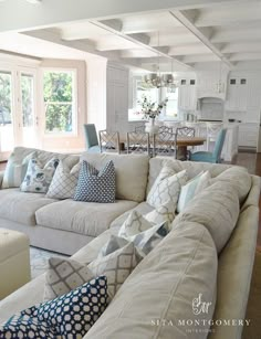 a living room filled with white furniture and lots of pillows on top of it's couches