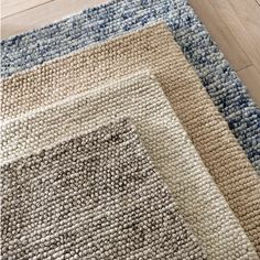 three rugs on the floor in different colors and sizes, one with a blue border