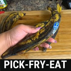 a person holding a banana on top of a wooden cutting board