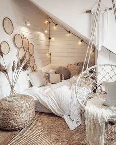 a bedroom with white bedding and hanging decorations on the wall, including a hammock chair